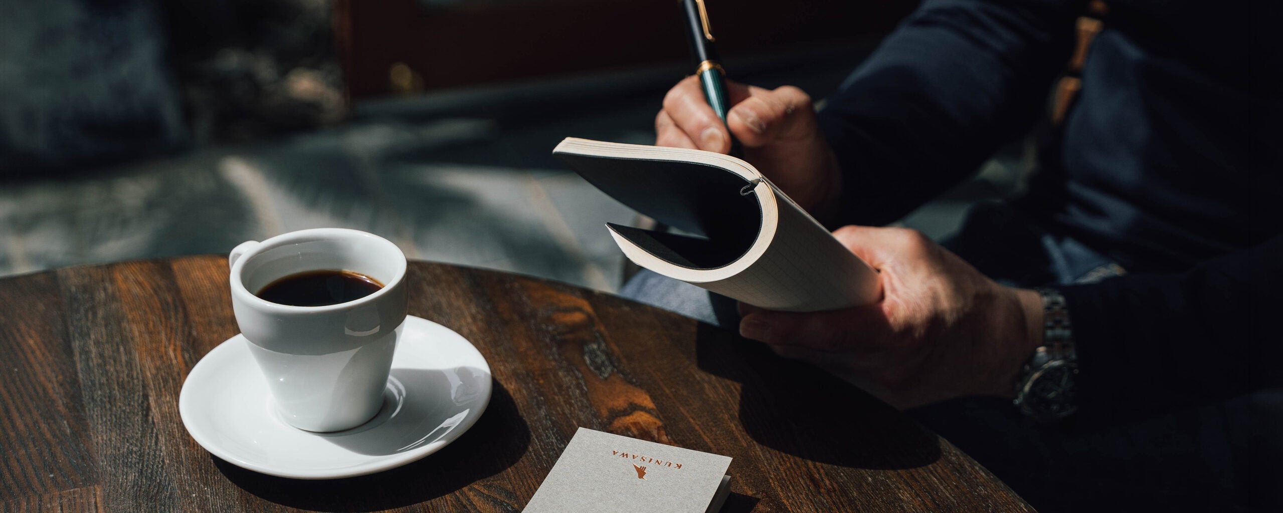 コーヒーと手帳に書きものをする手元