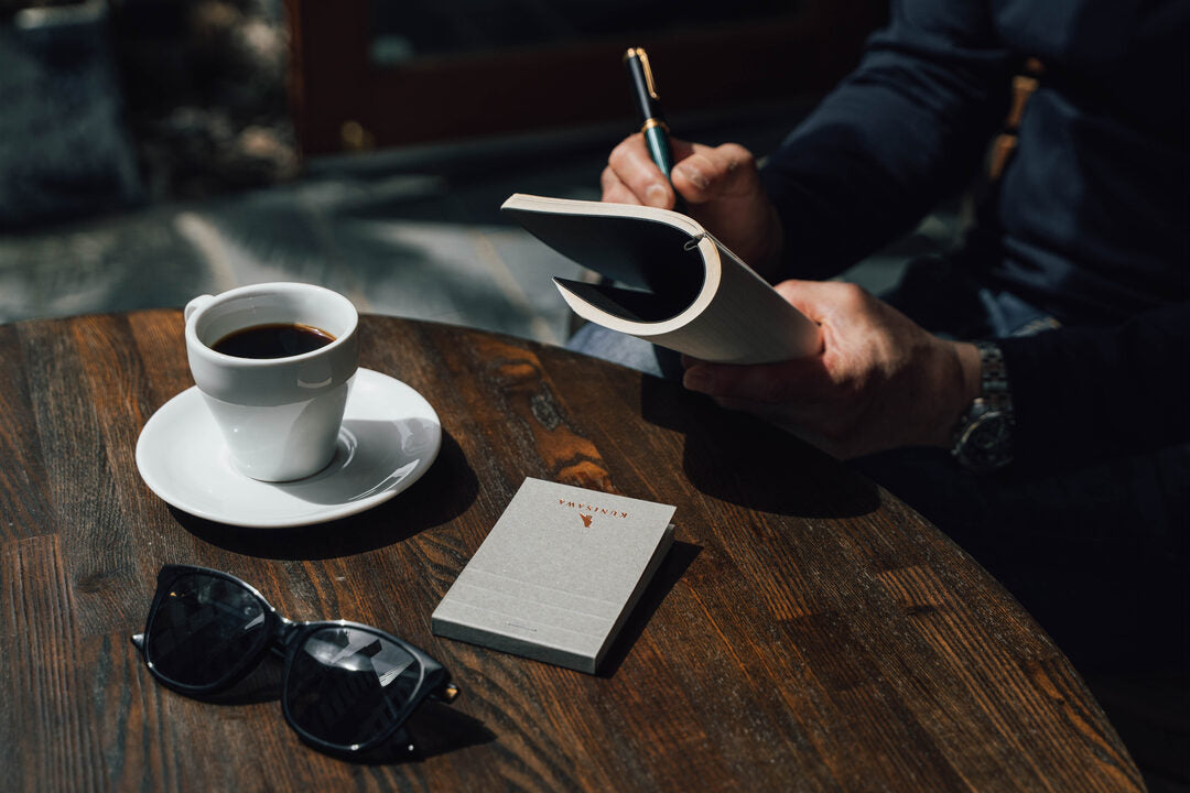 コーヒーと手帳に書きものをする手元